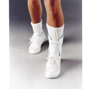 Person wearing white sneakers and white socks with green stripes.