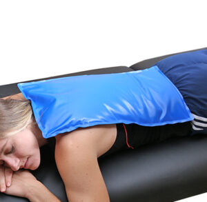 Woman relaxing with a blue ice pack on her shoulder.