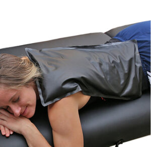 Person lying on a massage table with a hot pack on their back.