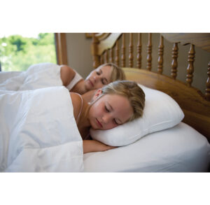 A couple peacefully sleeping in bed under white sheets.
