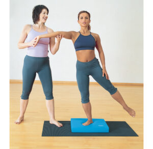 Two women practicing balance exercises in a fitness studio.