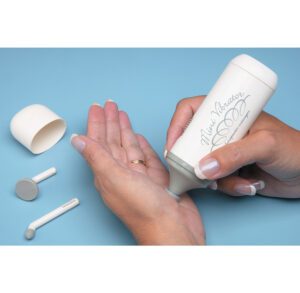 Person applying lotion on hand with bottle and cotton pads nearby.