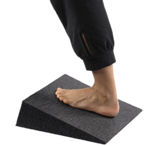 A bare foot stepping on a gray angled foam wedge.